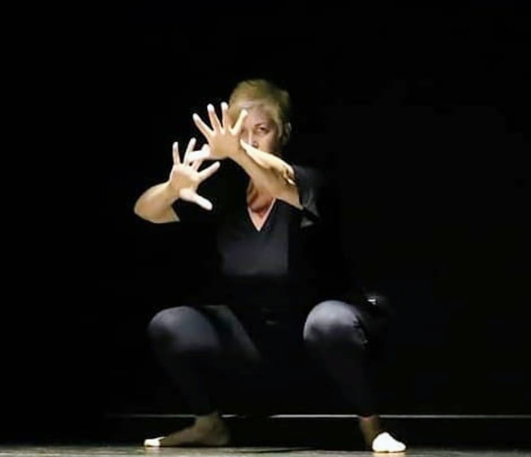 Nevena Mitić performing, crouched with her hands raised in front of her face